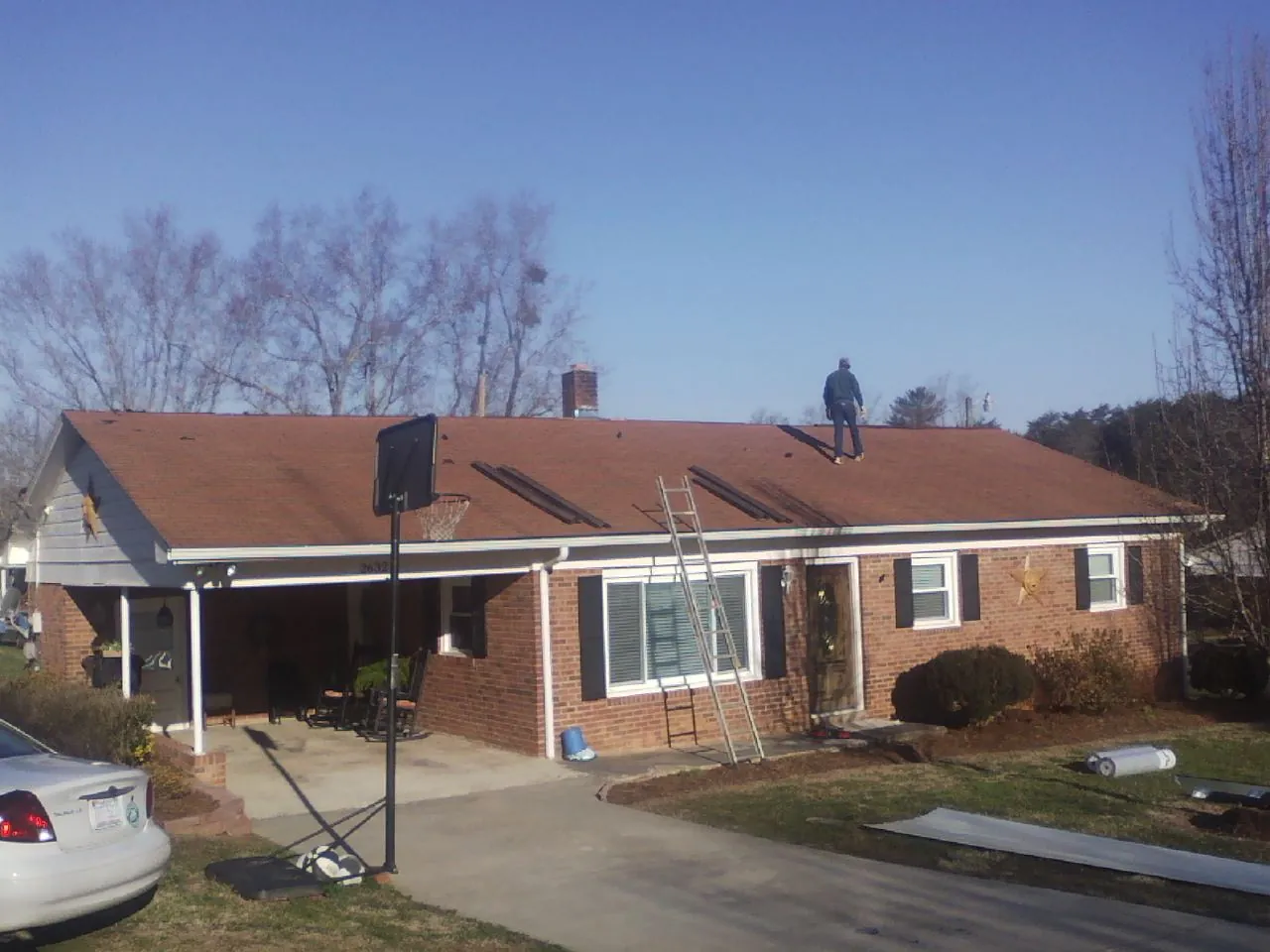 Roofer stripping a shingle roof on a brick ranch before metal panels in Villanova