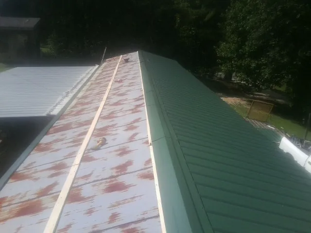 Old rusted panels beside newly installed green metal roofing — Wind Damage Roof Repair by Roofing Brothers in Villanova