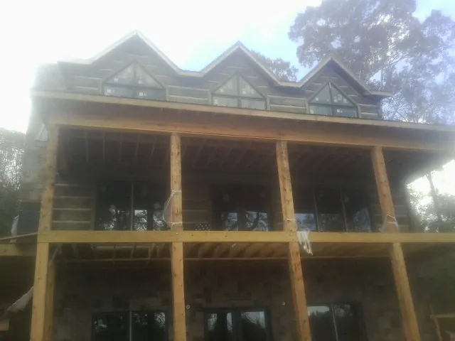 Dormers and porch framing on a large log home under construction — Roof Coating work by our crew in Villanova