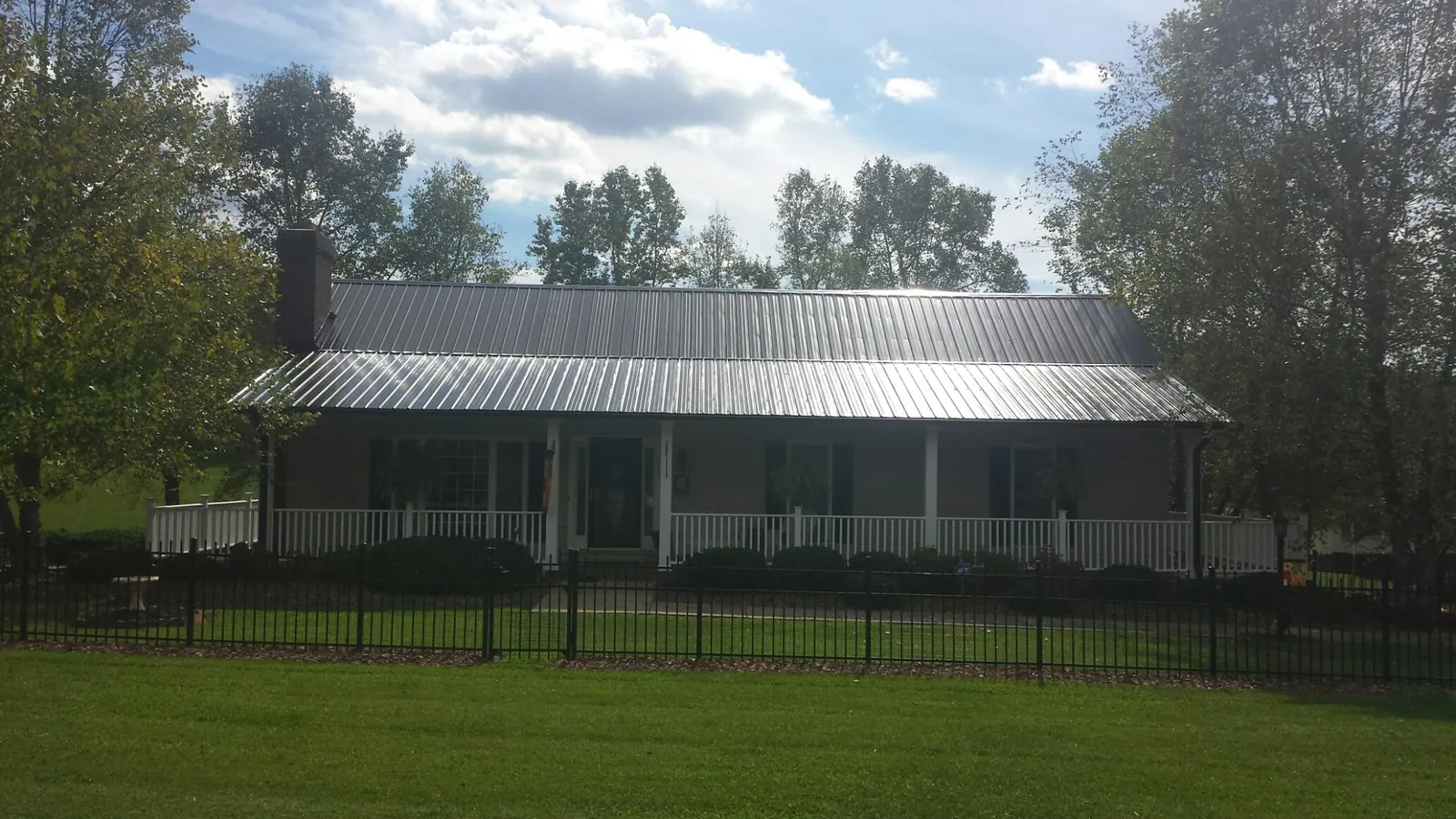 Gray metal roof on a brick ranch with a full width front porch — Gutter Guard Installation work by our crew in Villanova