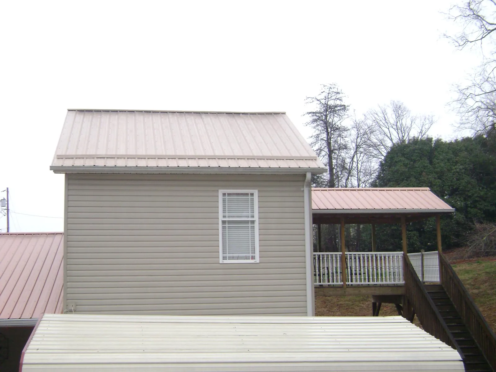 Tan metal roofs on a two story addition and attached porch, from a Roof Replacement job in Villanova