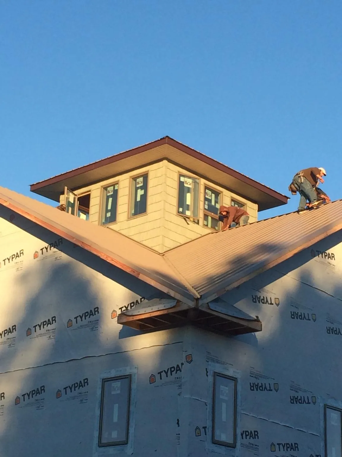 Roofers working around a rooftop cupola on a new metal roof at sunset — Roof Waterproofing in Villanova by Roofing Brothers